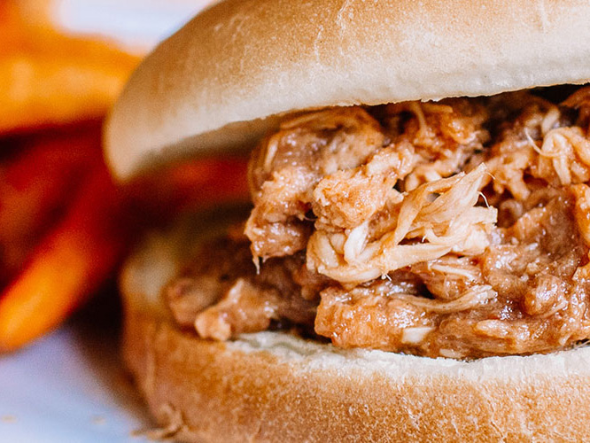 BBQ Pulled Chicken Sandwich with sweet potato fries in the background