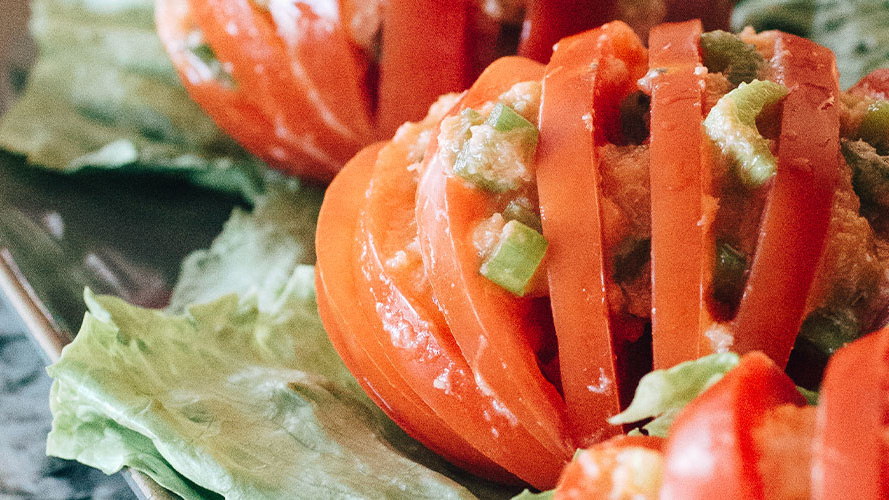 Crabmeat Tomato Accordions sitting on top of a piece of lettuce