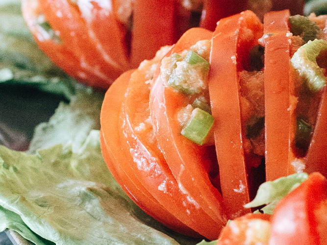 Crabmeat Tomato Accordions sitting on top of a piece of lettuce