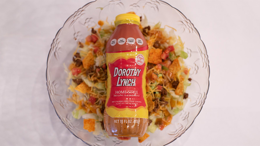 Dorothy Lynch Taco Salad in a clear bowl with a bottle of Dorothy Lynch laying ontop inside the bowl