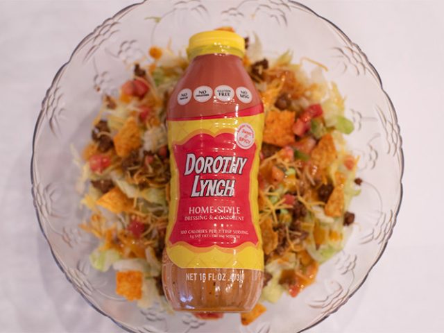 Dorothy Lynch Taco Salad in a clear bowl with a bottle of Dorothy Lynch laying on top inside the bowl