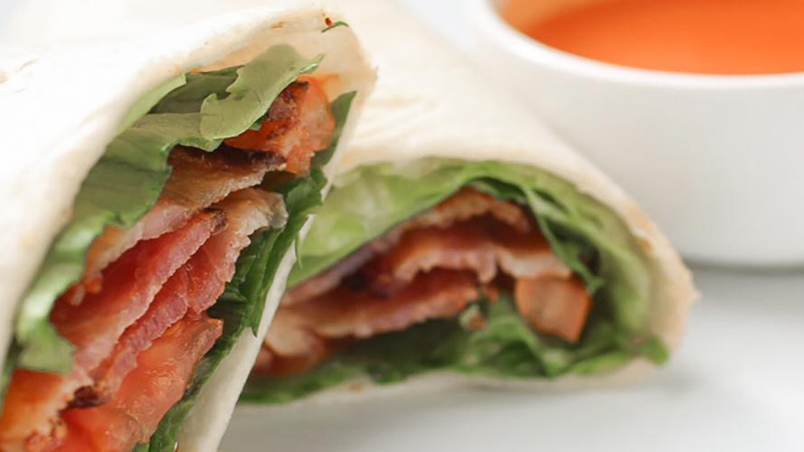 Bacon, Lettuce, Tomato Wrap with a small white bowl of Dorothy Lynch next to it for dipping