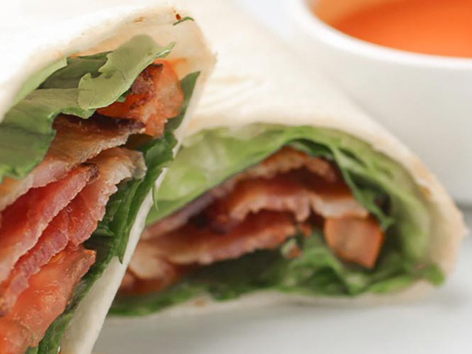 Bacon, Lettuce, Tomato Wrap with a small white bowl of Dorothy Lynch next to it for dipping