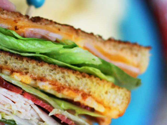 Side cross section view of a Grilled Club sandwich with lettuce, deli meat, and Dorothy Lynch