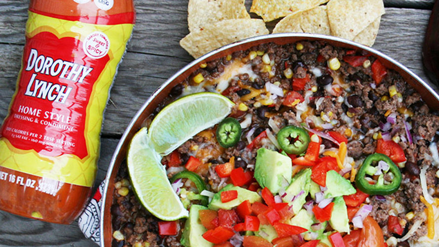 Mexican Ground Beef Skillet in a pan with tortilla chips, limes, and a Bottle of Dorothy Lynch in frame