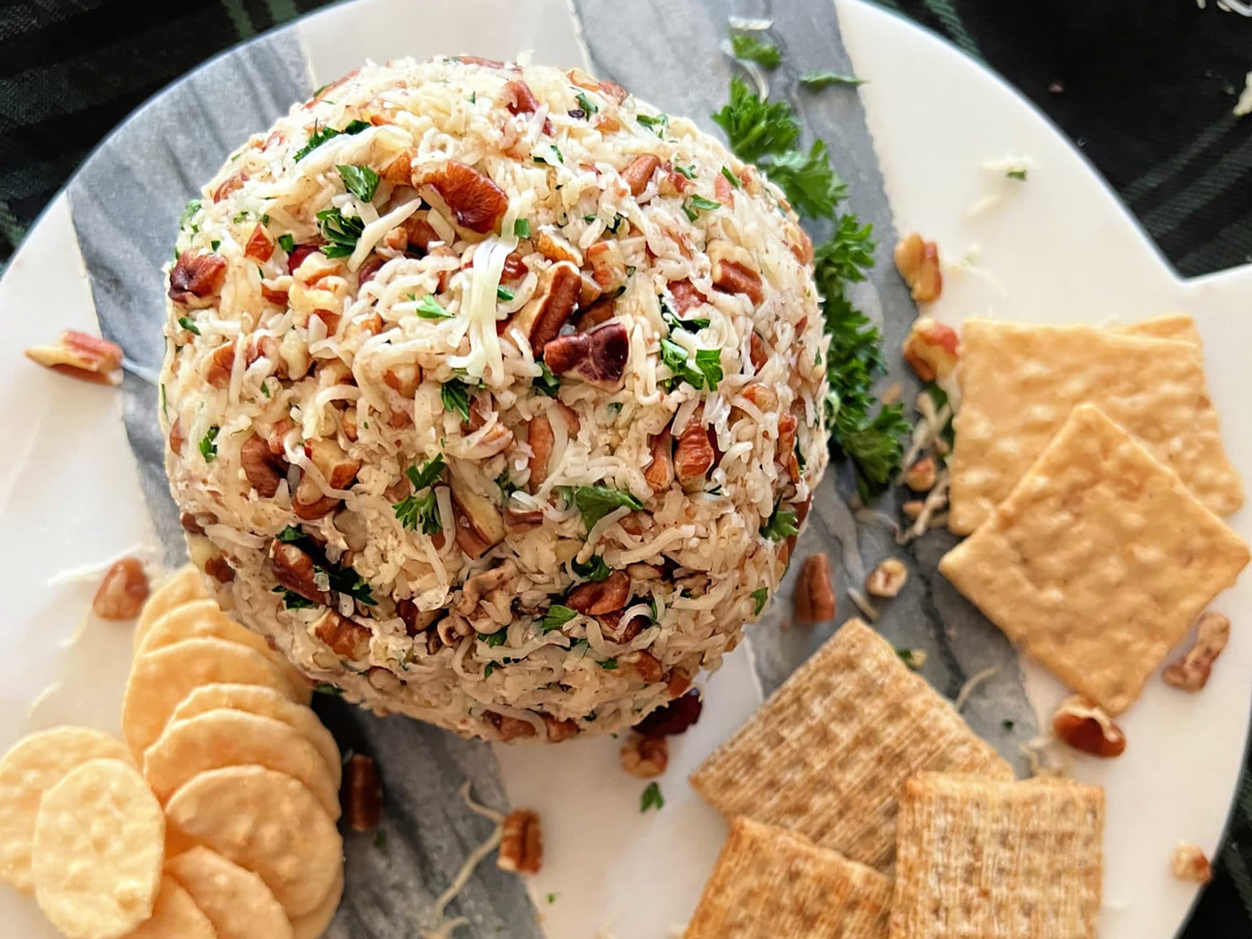 Dorothy Lynch Cheese Ball Appetizer Recipe on a marble serving plate with crackers surrounding