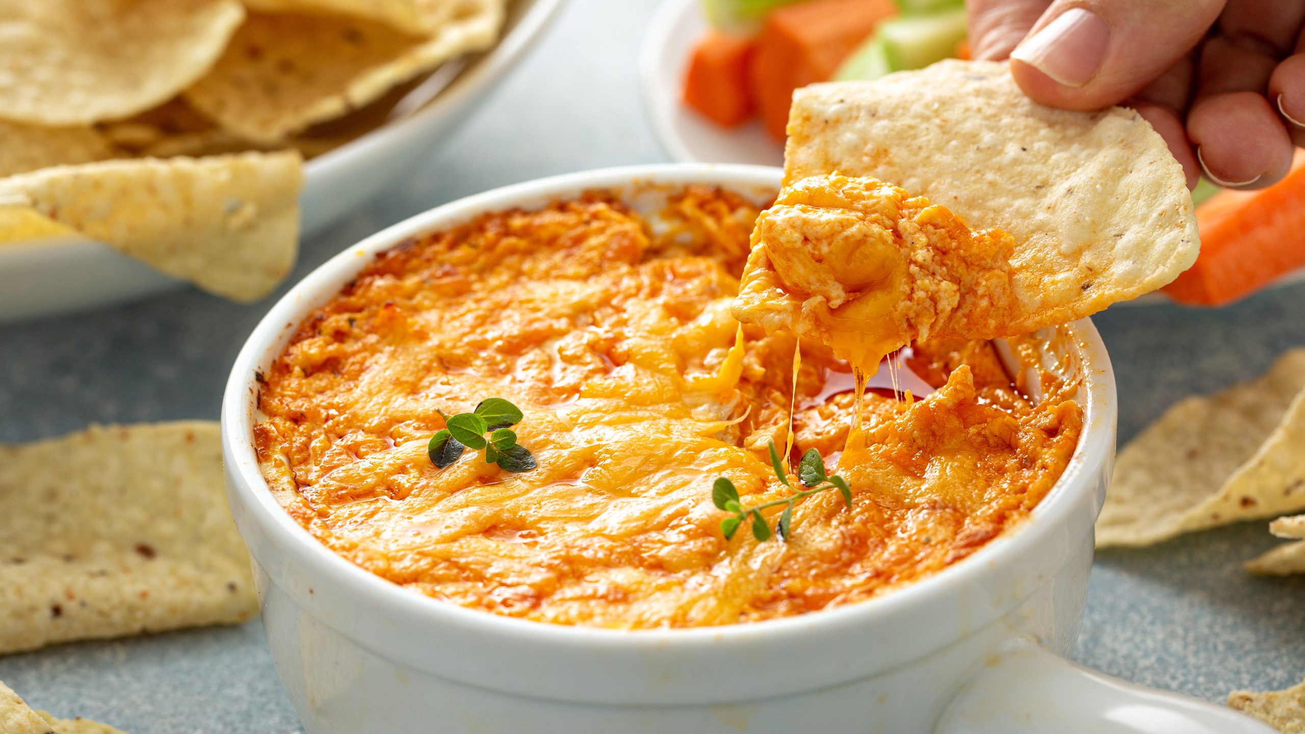 Dorothy Lynch Cheesy Buffalo Chicken Dip Recipe with someone actively dipping a chip into the dip