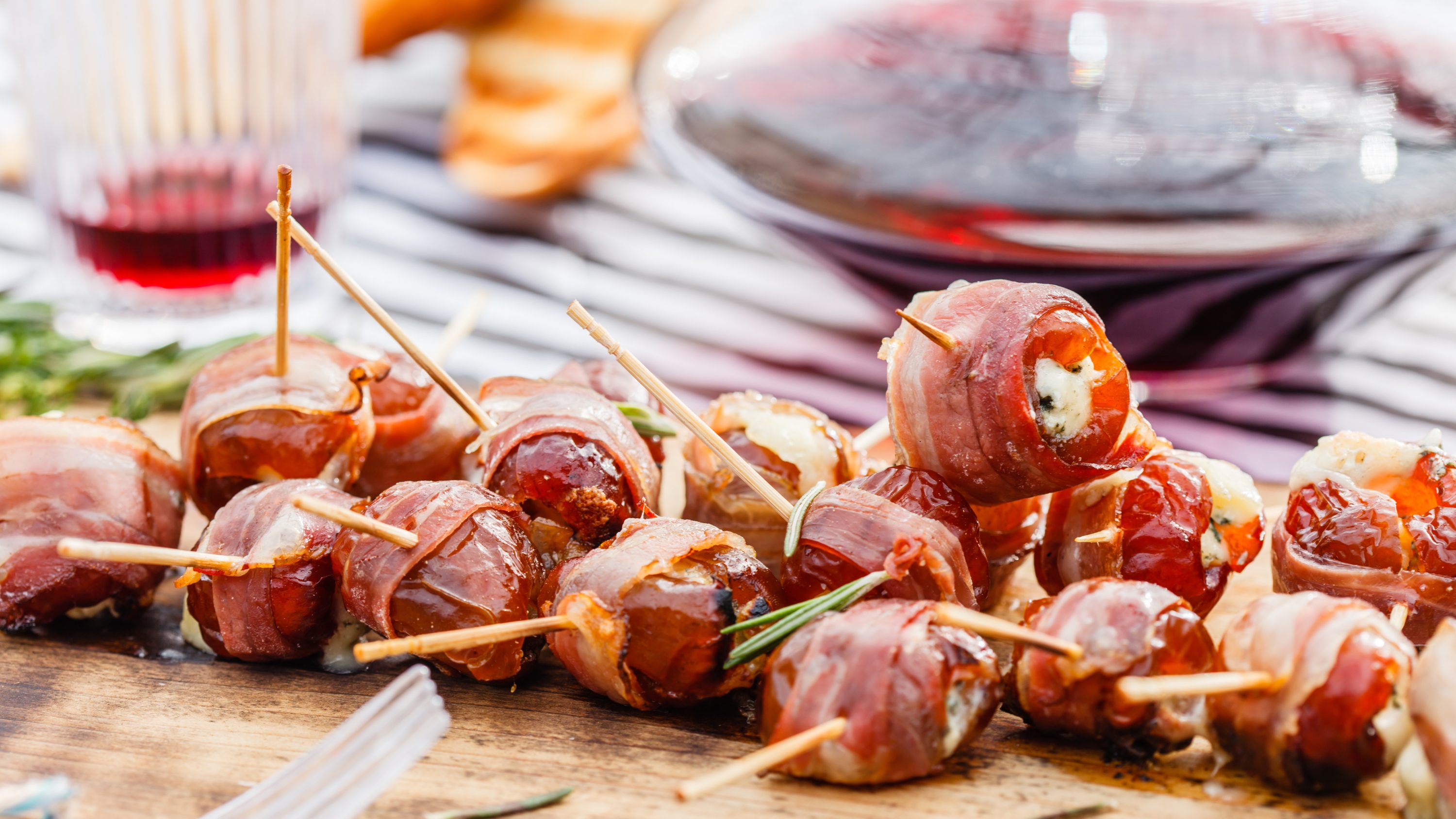 Dorothy Lynch Glazed Bacon Stuffed Dates with toothpicks stuck in them all- on a wooden serving tray