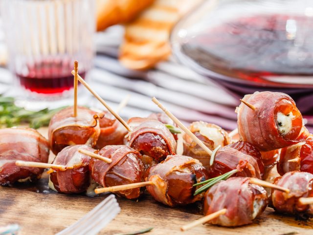 Dorothy Lynch Glazed Bacon Stuffed Dates with toothpicks stuck in them all- on a wooden serving tray