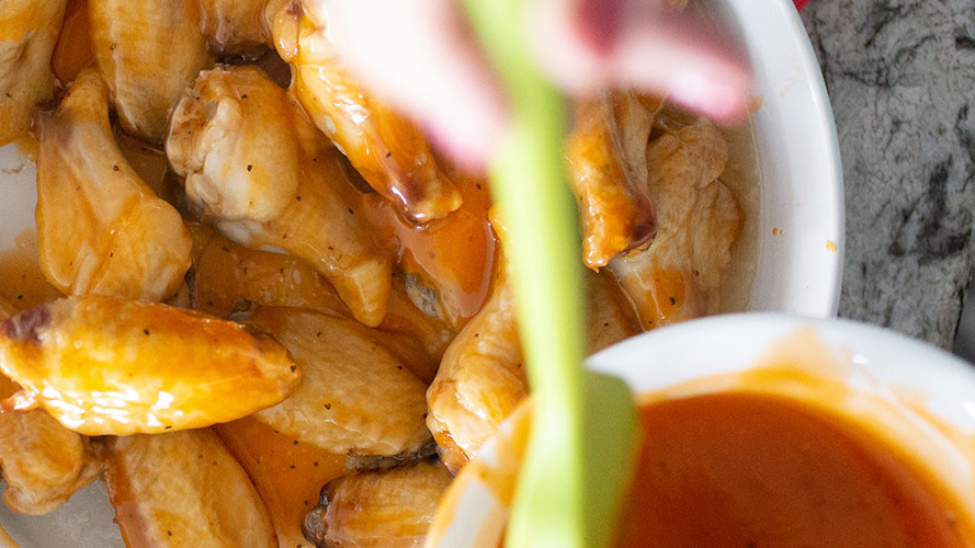 Pouring a bowl of Dorothy Lynch on Honey Glazed Wings with Dorothy Lynch on a white plate