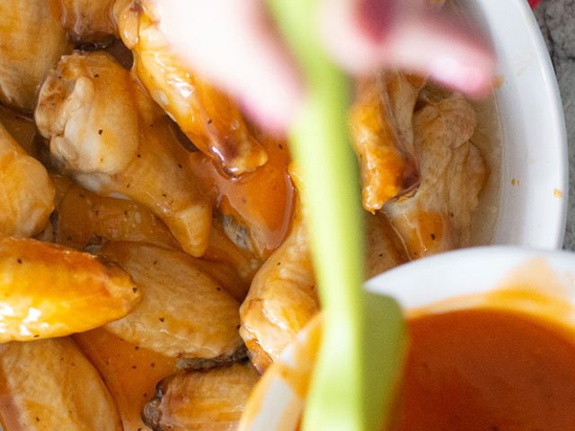 Pouring a bowl of Dorothy Lynch on Honey Glazed Wings with Dorothy Lynch on a white plate