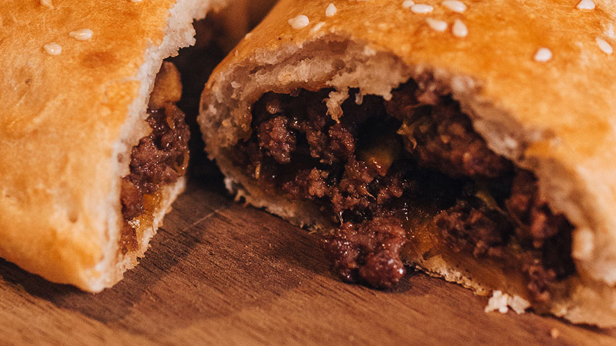 Spicy Asian-Inspired Calzones cut open so you can see the filling sitting on a wooden board