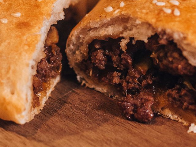 Spicy Asian-Inspired Calzones cut open so you can see the filling sitting on a wooden board